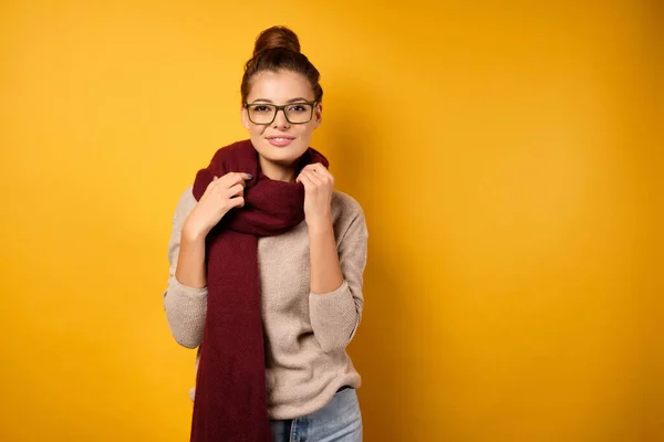 스웨터를 입고 서서 스카프를 들고 카메라 앞에서 미소를 짓는 아름다운 브루 네트 — 스톡 사진