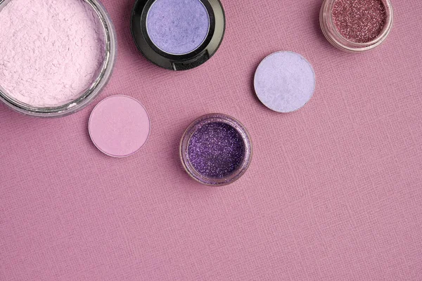 Eye shadow and powder are placed on the top edge on a dirty pink textured background — Stock Photo, Image