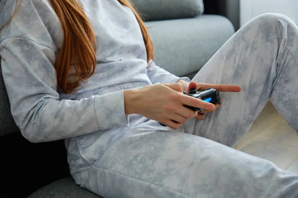 Plan rapproché des mains d'une fille aux cheveux roux avec une console de jeu assise sur le sol . — Photo