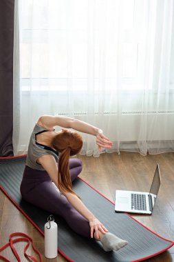 Kız dizüstü bilgisayarın önünde evi germekle meşgul, arkadan çekilmiş bir çerçeve.