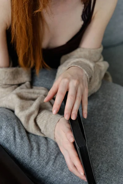 Les mains d'une fille rousse sur un livre noir. se concentrer sur ses doigts . — Photo