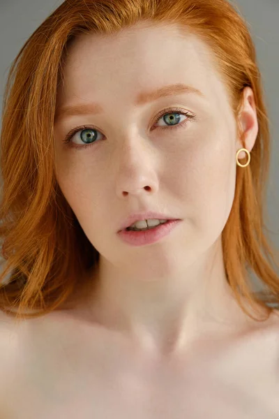 Ett nära porträtt av en rödhårig flicka med blå ögon i solljuset. Stockbild