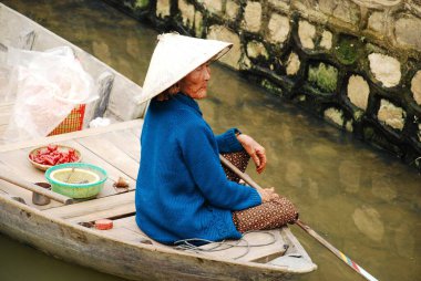 Yaşlı Vietnamlı kadın nehirdeki teknede