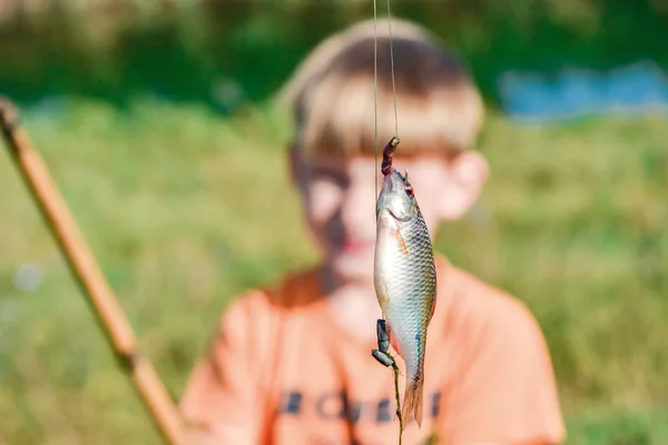 Chytil rybu na rybářském prutu zavěšeném na háku, zblízka. — Stock fotografie