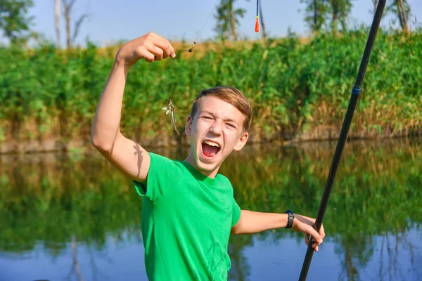 Un ragazzo di pesca sta cercando di mangiare un pesce catturato per canna da pesca . — Foto Stock