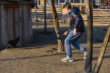 Fotoğrafçının tavuğun peşinden koştuğu ve kameraya monte edilmiş bir şekilde çektiği adam. Çiftlikte video çekimi..