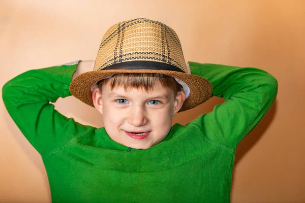 Ragazzo allegro e felice in un cappello di paglia e vestiti verdi sorridenti e guardando la fotocamera . — Foto Stock