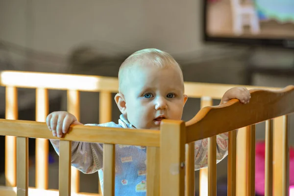 Un bambino piccolo nel box sullo sfondo della TV incustodito . — Foto Stock