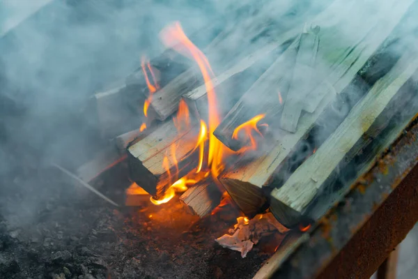 Queimando troncos para acender um fogo, chama e fumaça em chamas. Logs em um churrasco para fritar carne . — Fotografia de Stock