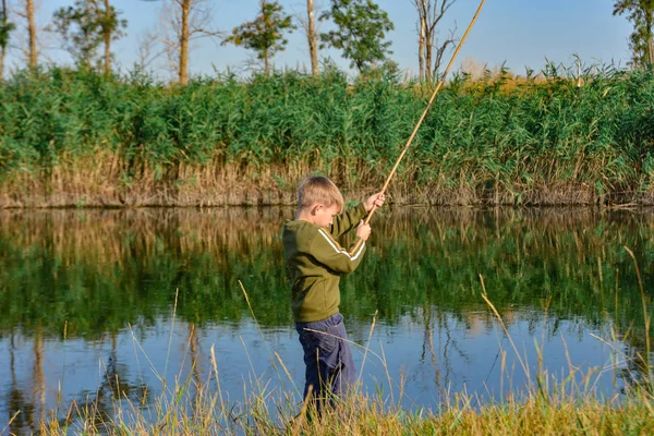 少年は釣竿を水の上に置いて釣りをする。. — ストック写真