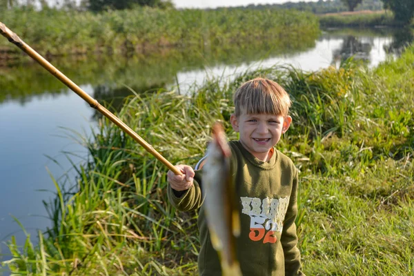 A fiú megmutatja a halat, amit egy horgászboton fogott.. — Stock Fotó