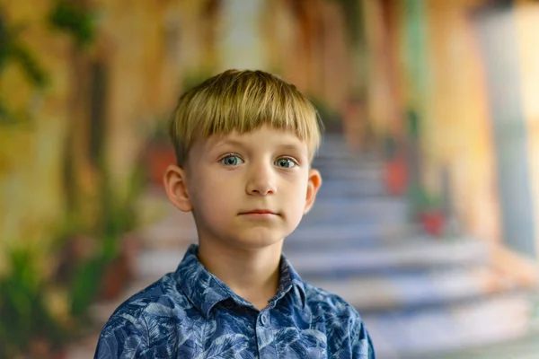 Un niño sobre el telón de fondo de edificios antiguos de la ciudad mira a la cámara cerca de las escaleras . —  Fotos de Stock