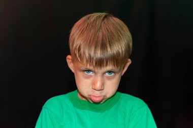 Siyah arka planda yeşil tişörtlü bir çocuk..