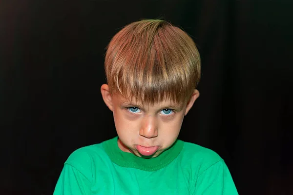 검은 배경에 녹색 티셔츠를 입은 기분나쁜 소년. — 스톡 사진