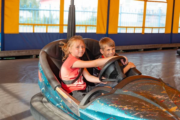 Crianças andam em carros elétricos em um parque de diversões . — Fotografia de Stock