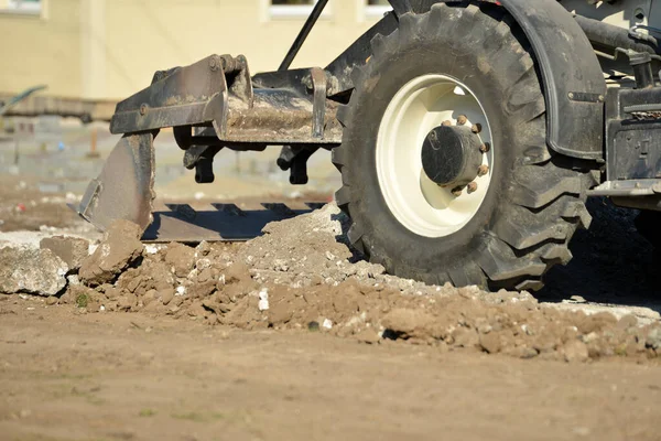 Sebuah traktor dengan ember melakukan pekerjaan konstruksi pada membersihkan wilayah di lokasi konstruksi . — Stok Foto