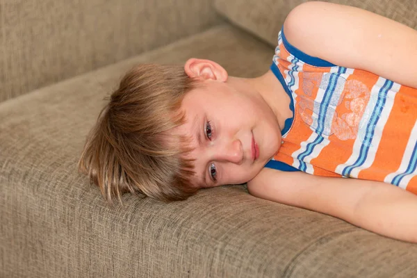 Сумний і сумний хлопчик лежить на дивані . — стокове фото
