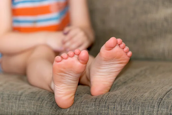 Beine eines Jungen, der auf einem Sofa in Großaufnahme sitzt. — Stockfoto