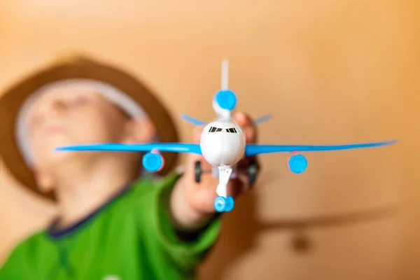 Um rapaz de chapéu de palha segura um avião infantil na mão . — Fotografia de Stock