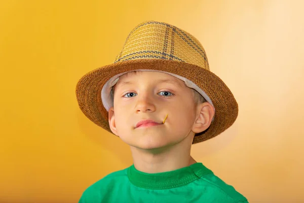 Un niño con sombrero de paja tiene un palillo en los dientes. . —  Fotos de Stock