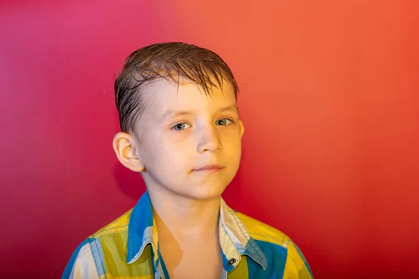 Ekose gömlekli ve kırmızı arka planda saçları olan bir çocuk. — Stok fotoğraf