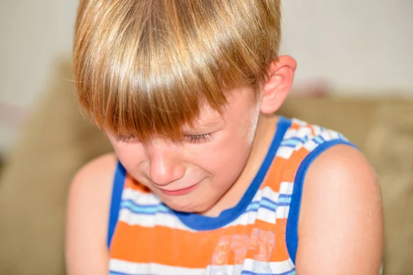 Хлопчик сидить і плаче на дивані зі сльозами після покарання . — стокове фото