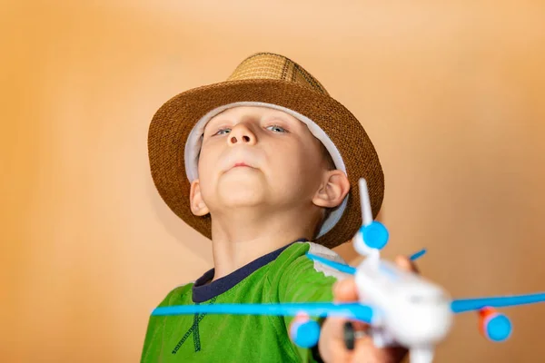 Un niño con sombrero de paja sostiene un avión infantil en su mano . —  Fotos de Stock