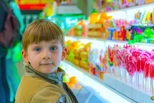 Sorpreso e gioioso ragazzo in un negozio di caramelle . — Foto Stock