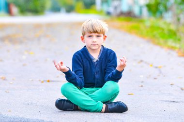 Çocuk açık gözlerle meditasyon yapıyor, sokakta oturuyor..