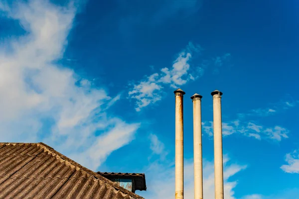 Dak van een woongebouw en schoorsteen tegen een bewolkte blauwe lucht. — Stockfoto