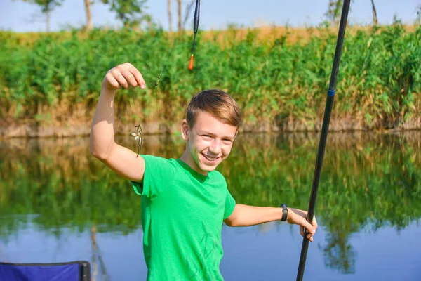 Ein Fischerjunge angelt nach einer Angel, ein fröhlicher und fröhlicher Kerl auf einem Fluss. — Stockfoto