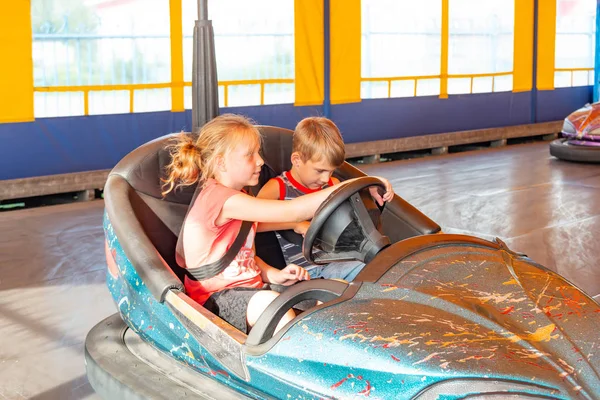 Crianças andam em carros elétricos em um parque de diversões . — Fotografia de Stock