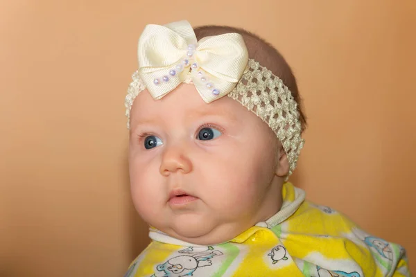 Retrato de uma menina com uma bandagem na cabeça sobre um fundo bege . — Fotografia de Stock