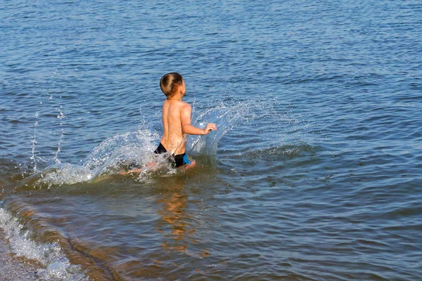 Pojken hoppar och dyker i havet. — Stockfoto