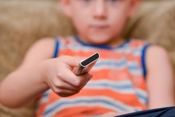 Мальчик на диване переключает пульт от телевизора . — стоковое фото