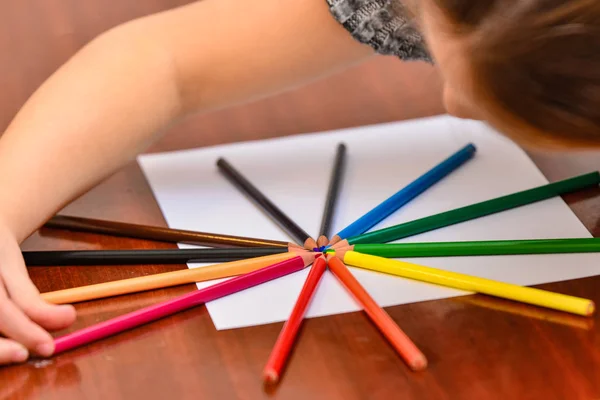 Ołówki kolorowe leżą na białym arkuszu na stole. — Zdjęcie stockowe