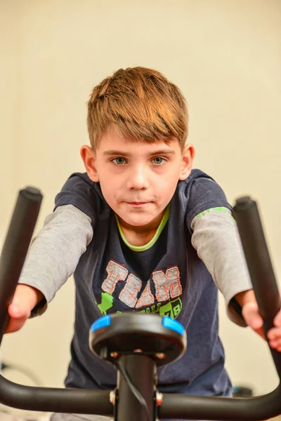 那男孩骑着固定自行车参加体育运动. — 图库照片