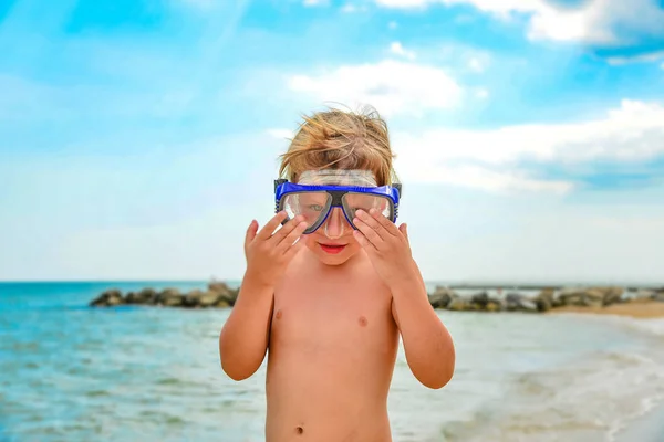 Chłopiec w okularach do nurkowania stoi na brzegu morza.. — Zdjęcie stockowe