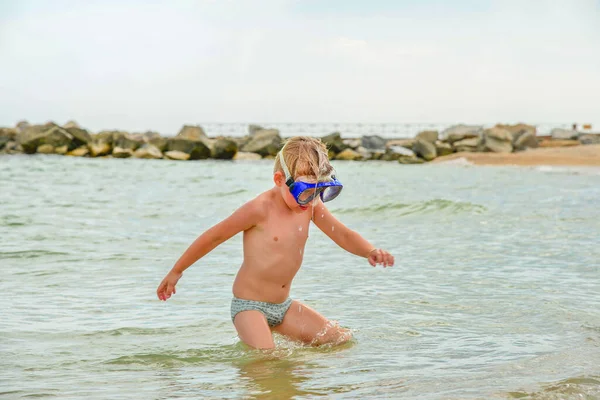 Chłopiec w okularach do nurkowania stoi na brzegu morza.. — Zdjęcie stockowe
