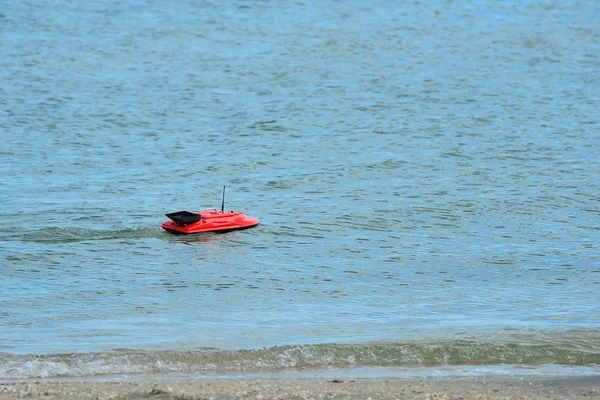 Um barco de brinquedo controlado por rádio flutua no mar . — Fotografia de Stock
