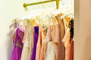 Bir moda mağazasının vitrininde akşam elbiseleri ve satılık bir mağazanın askısı..