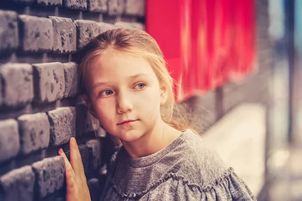 Retrato de una chica rubia cerca de una pared de ladrillo . —  Fotos de Stock