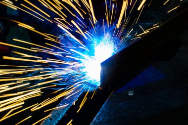 İşçi kaynakçı fabrikada üretim işlemleri yapıyor..