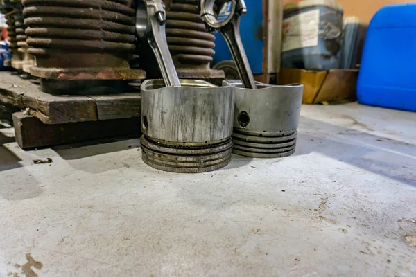 Piston with connecting rod next to internal combustion engine disassembled.