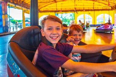 İki kardeş lunaparkta elektrikli araba kullanıyor..