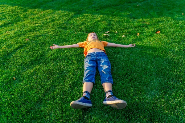 A fiú a zöld füvön fekszik, és az égre néz.. — Stock Fotó