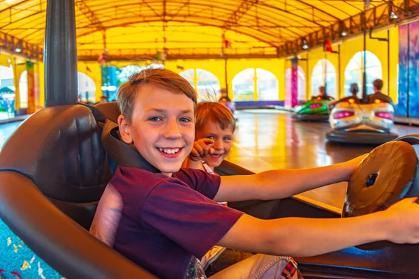 Dois irmãos montam carros elétricos em um parque de diversões . — Fotografia de Stock