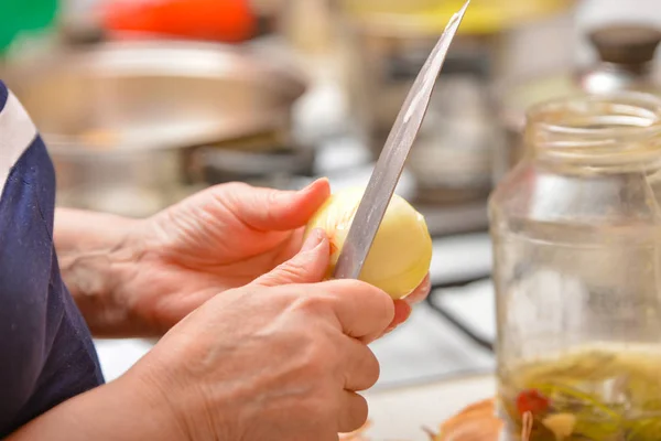 Cocinar en la cocina, pelar cebollas de la cáscara con un cuchillo — Foto de Stock