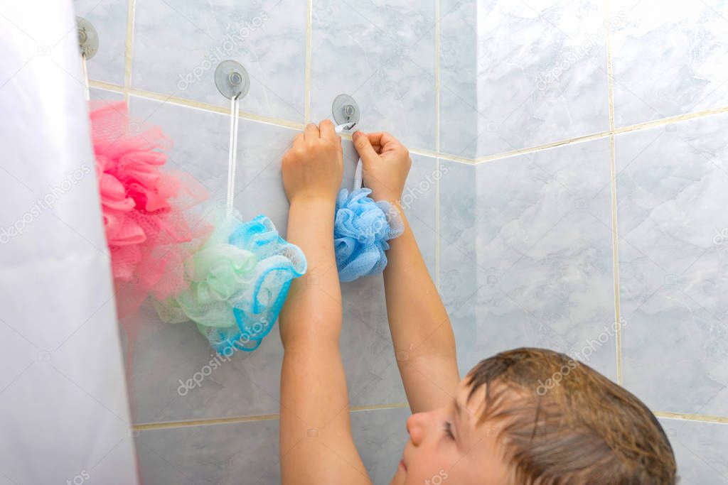 The boy in the shower after bathing hangs a washcloth in place