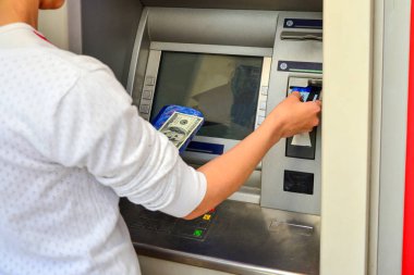 Bir kadın plastik kartla ATM 'den para çekiyor..